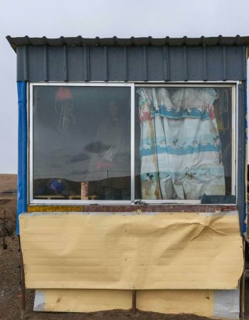 Simple rural hut with colorful curtains in a barren landscape showcasing survival and simplicity.